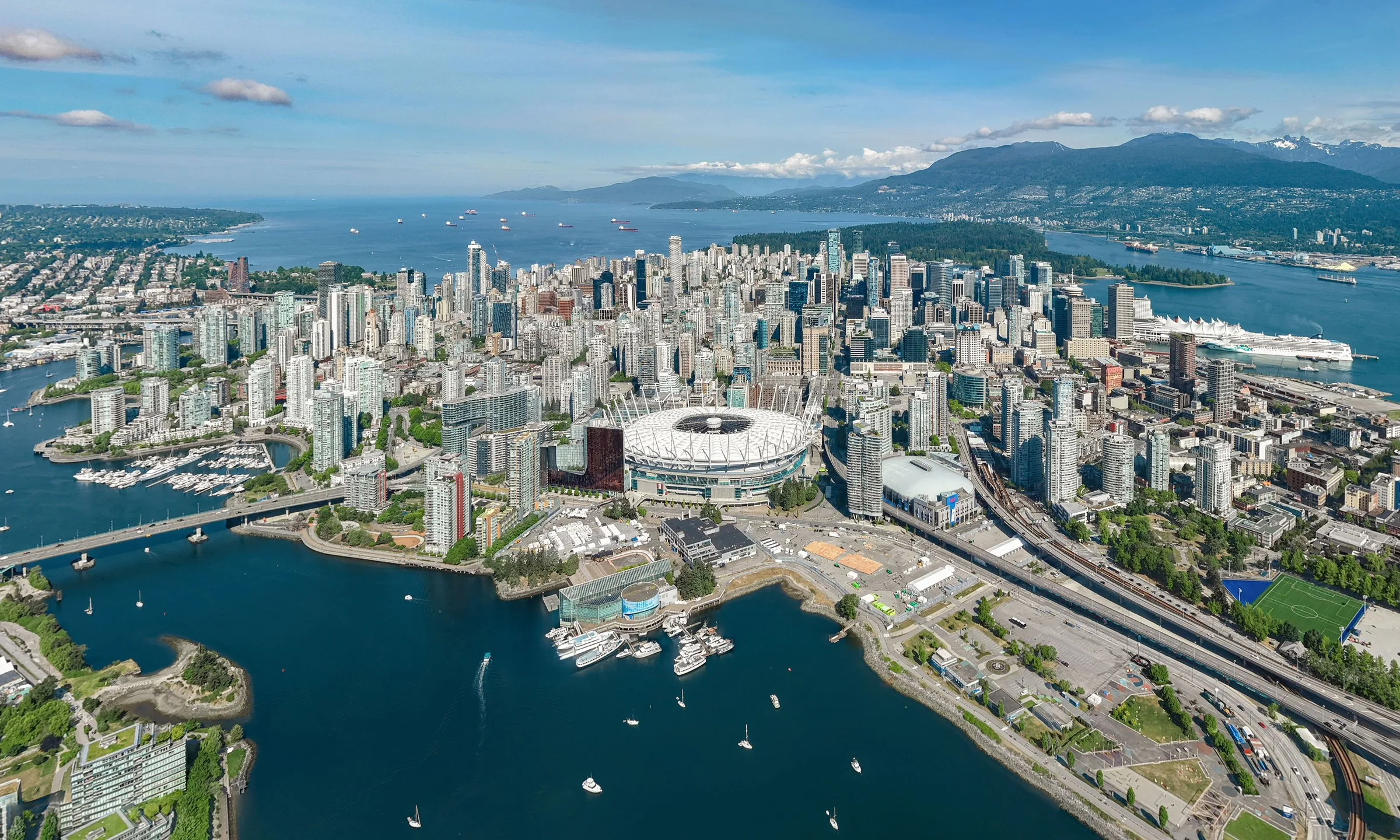 Aerial view of downtown Vancouver with its towers, False Creek and the mountains beyond.